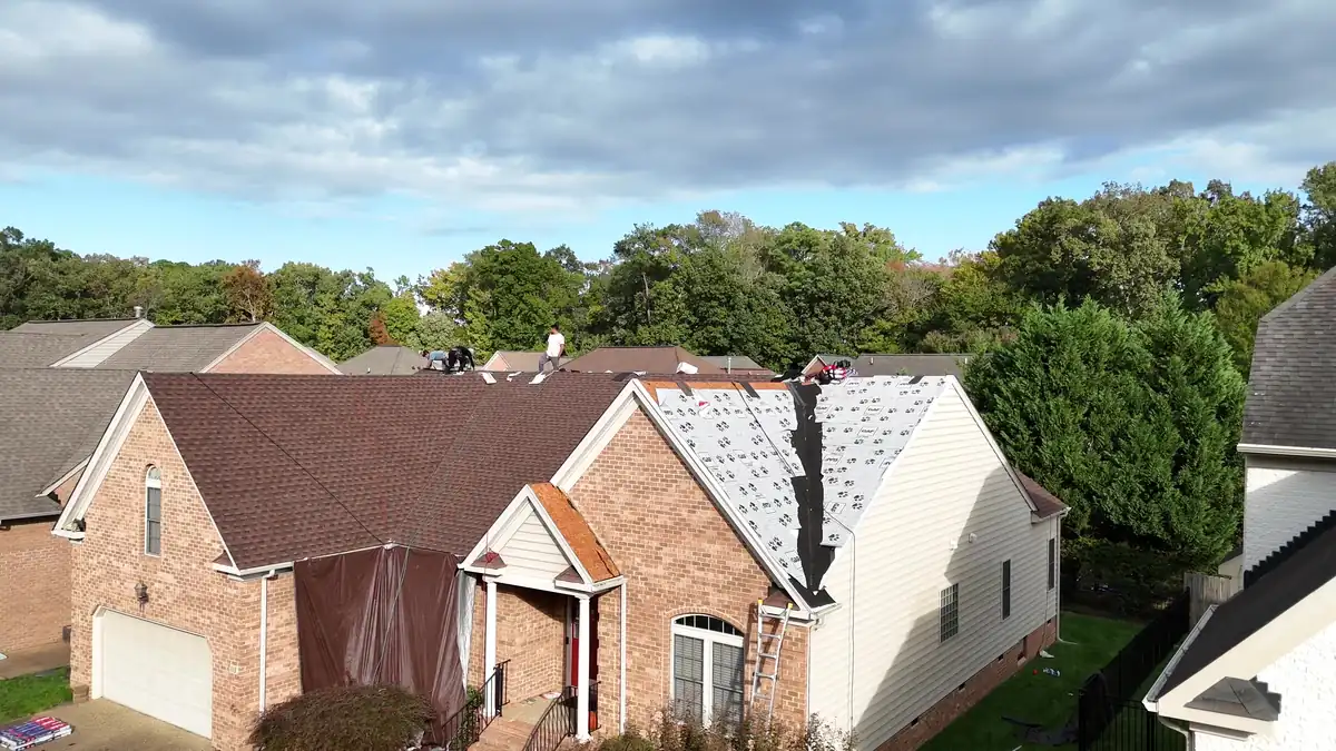 Drone view of a brick home mid re-roof, with underlayment on one roof section