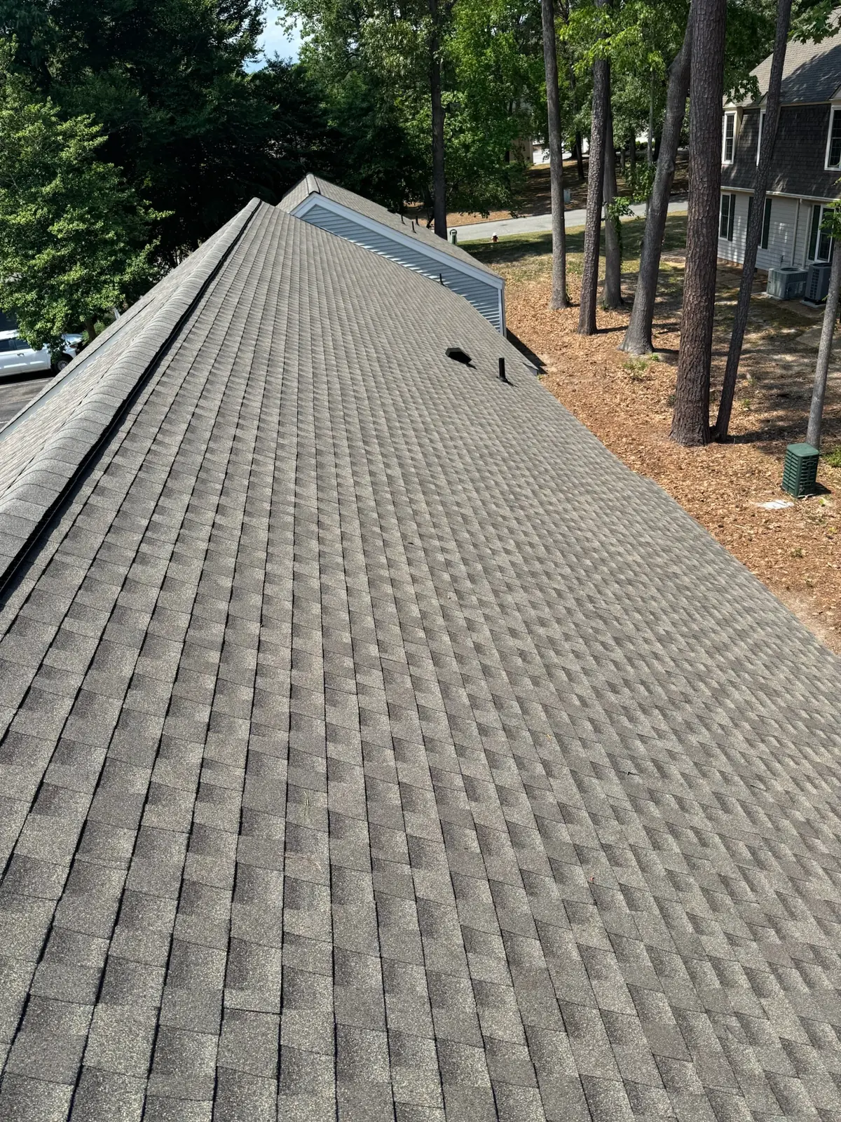 Finished shingle roof and ridge on a home surrounded by tall pines