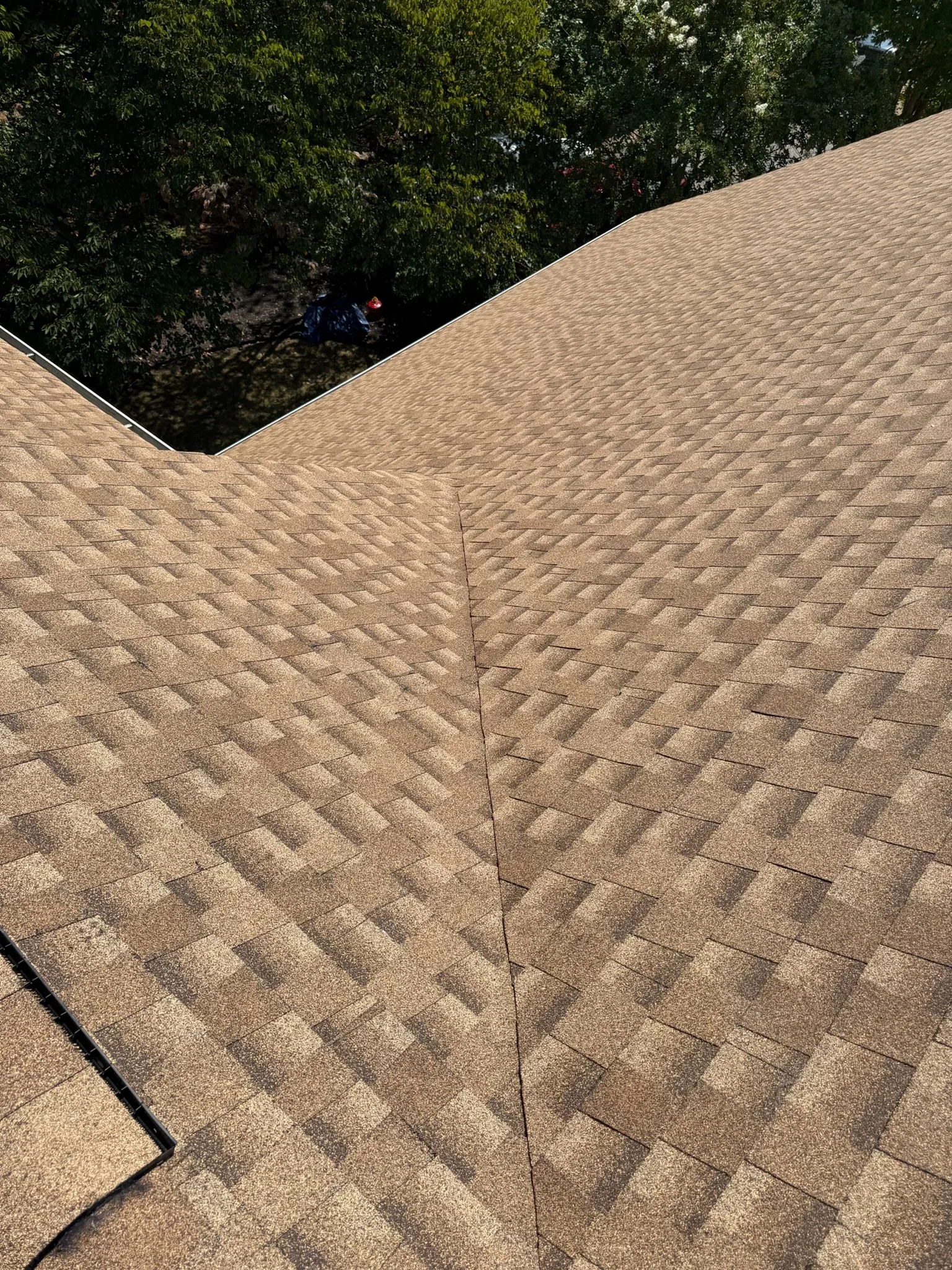 Tan architectural shingles installed on pitched roof with valley seam and clean alignment