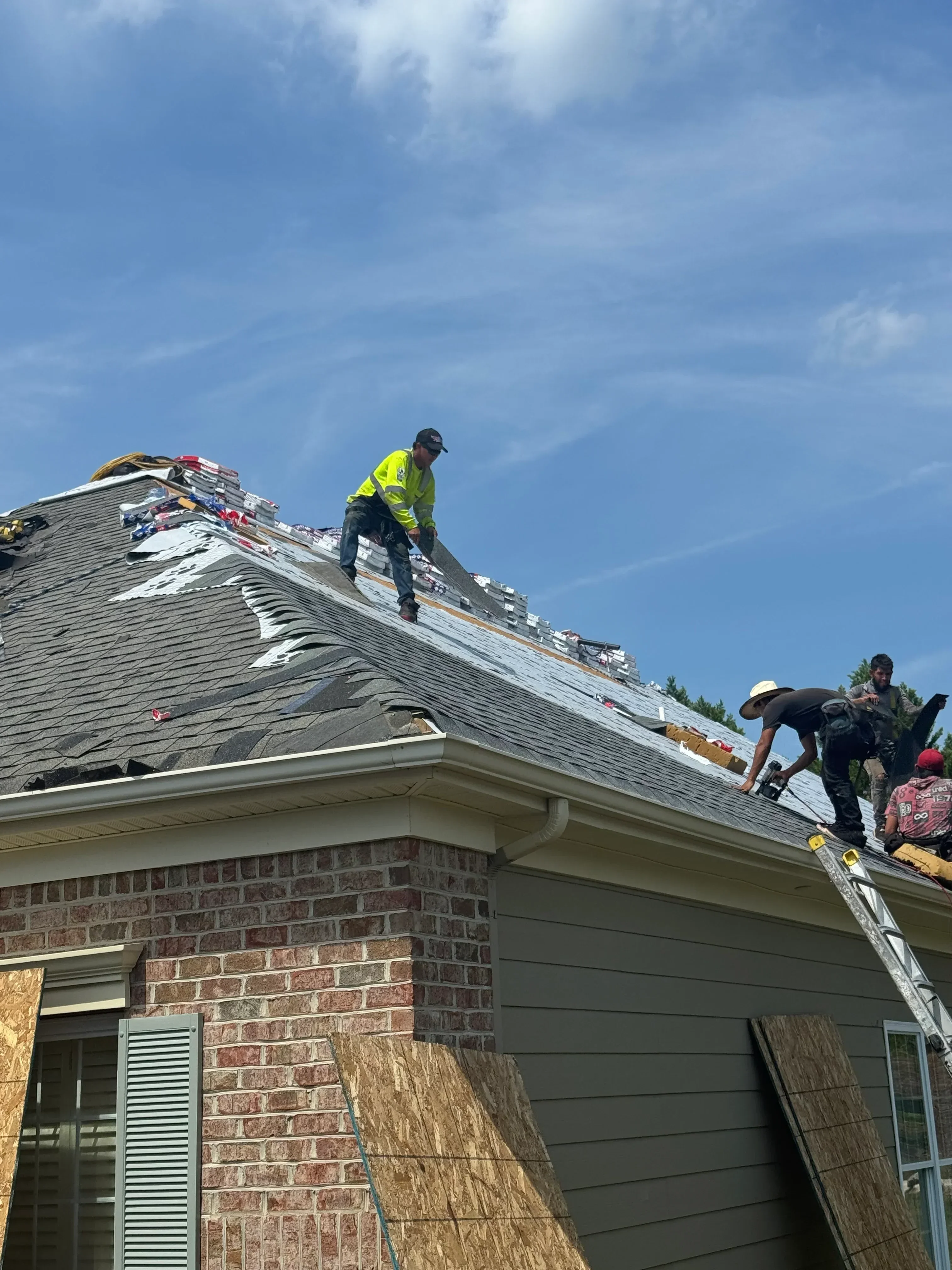 Standing seam metal roof installation with gray finish on residential home with brick exterior