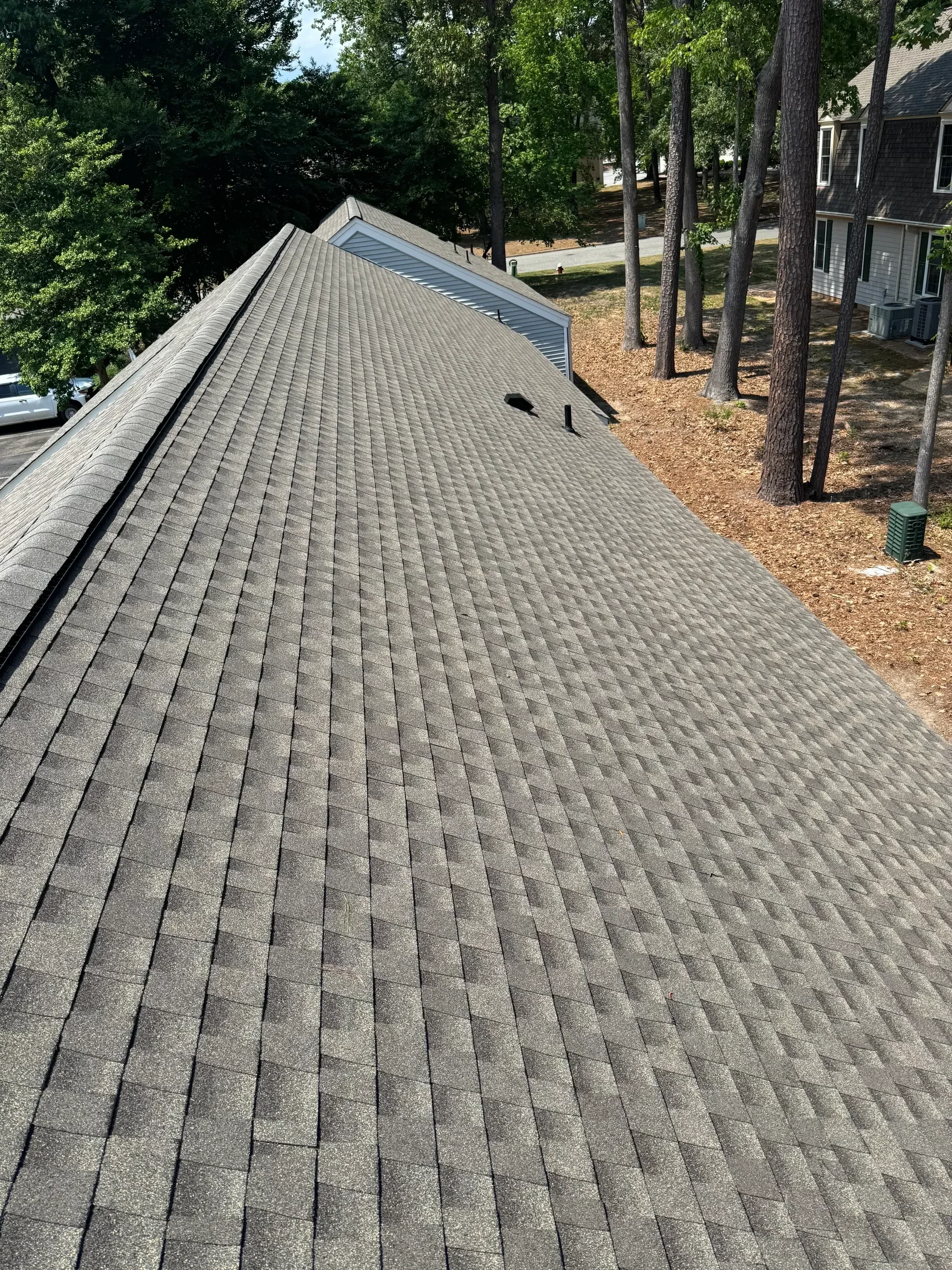 Gray architectural shingles installed on residential roof with metal gutter system