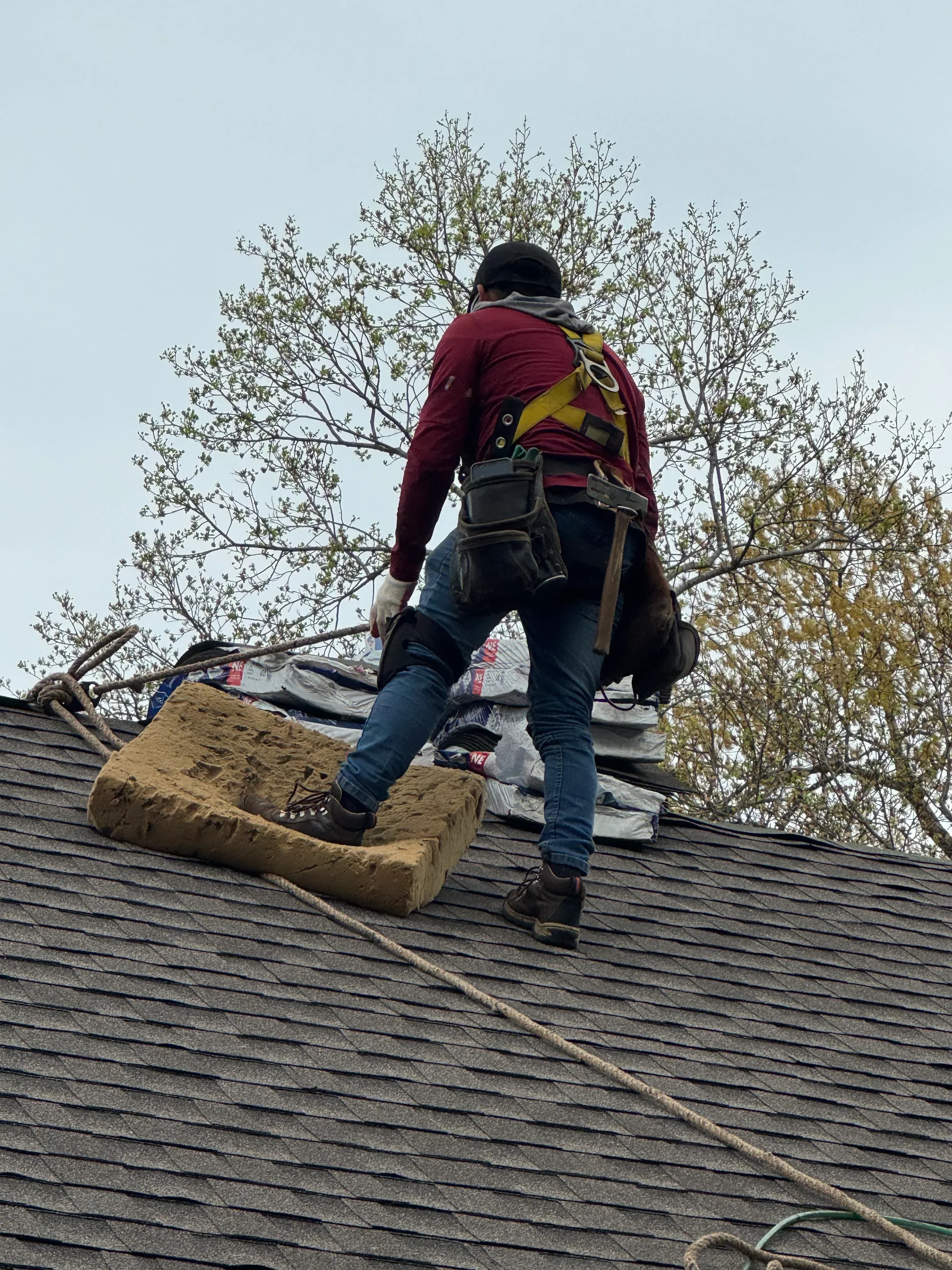 Worker installing standing seam metal roofing panels on residential structure