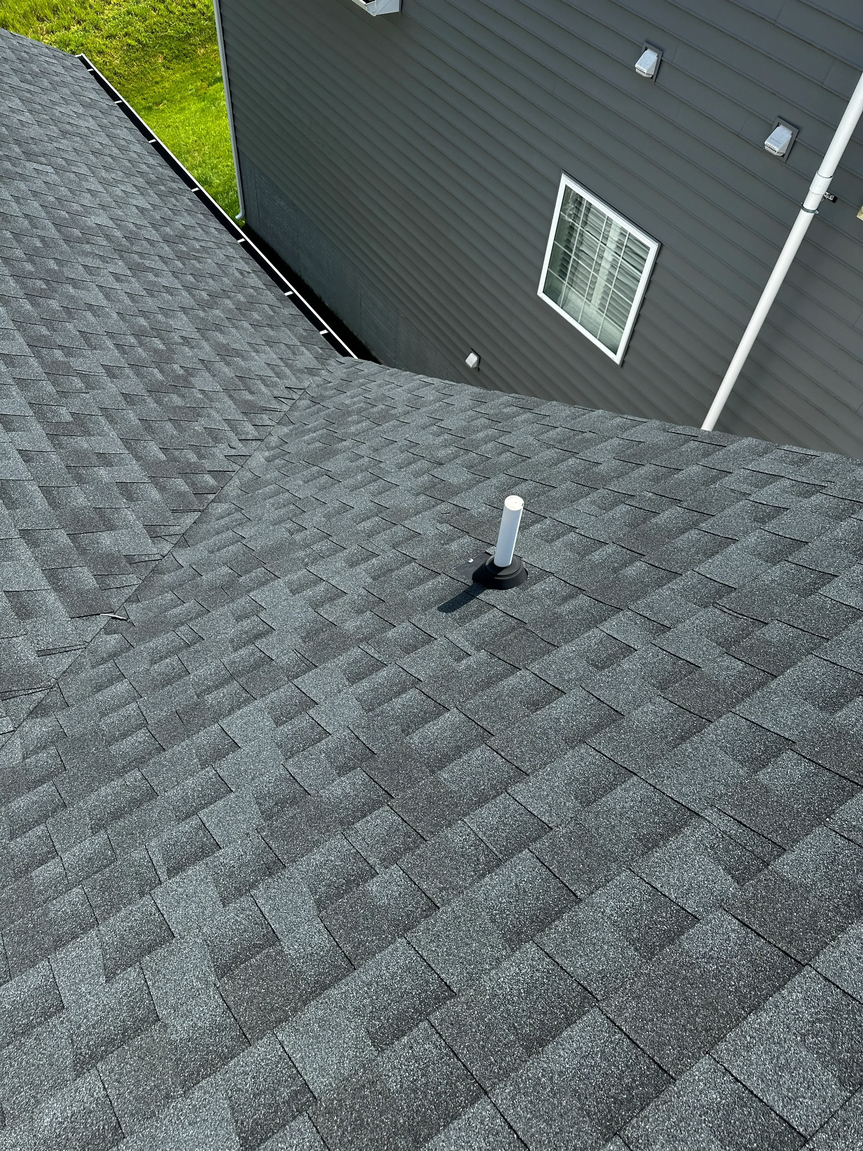 Gray dimensional asphalt shingles installed on pitched roof with metal drip edge and fascia