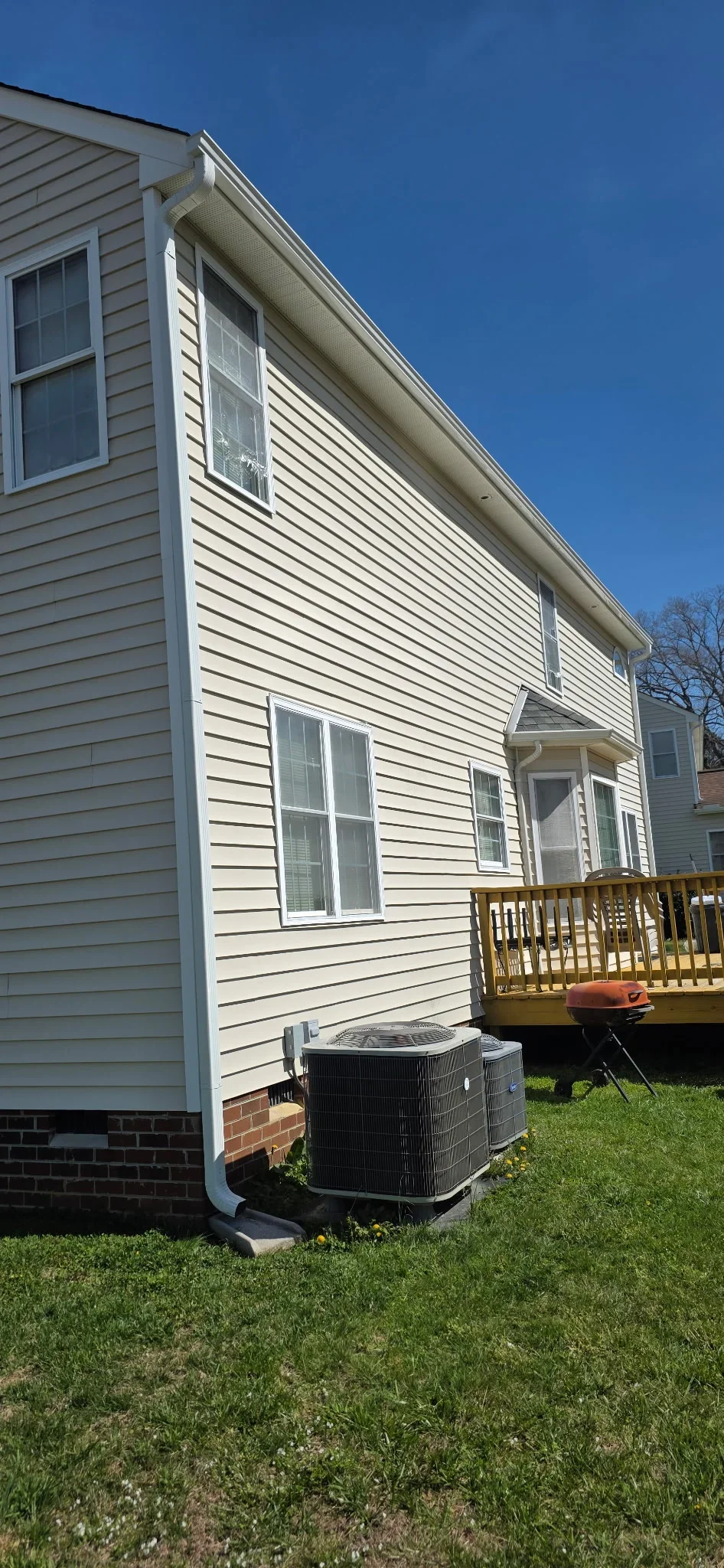 White vinyl siding with new gutters and downspout on residential home exterior