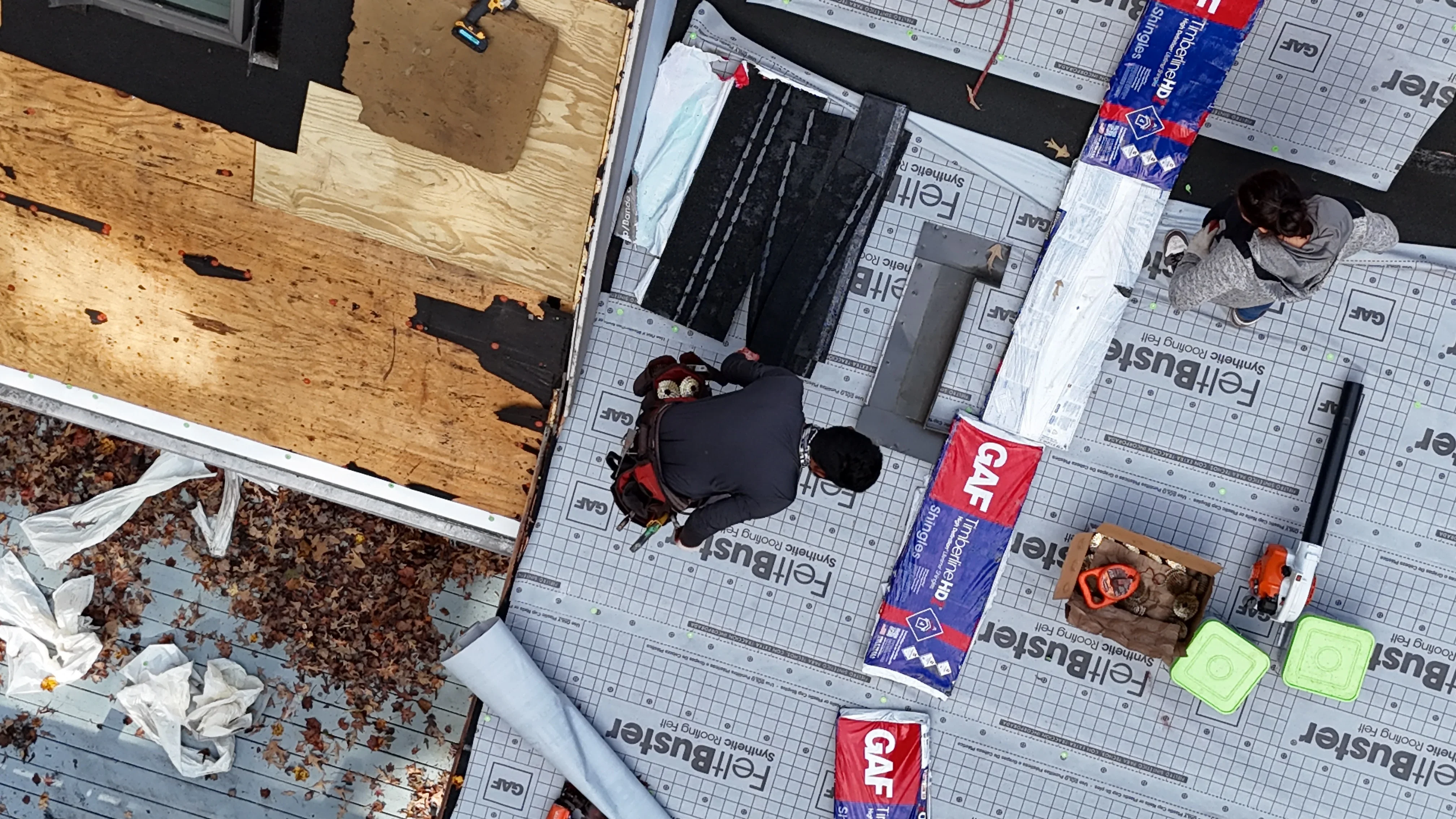 Roof replacement in progress with new underlayment, shingles, and removal debris visible
